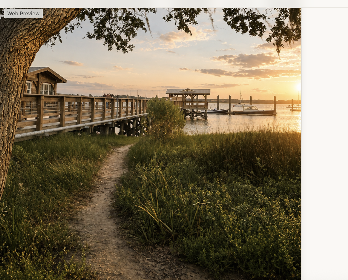 Waterfront path leading to a wooden pier and moored boats at sunset